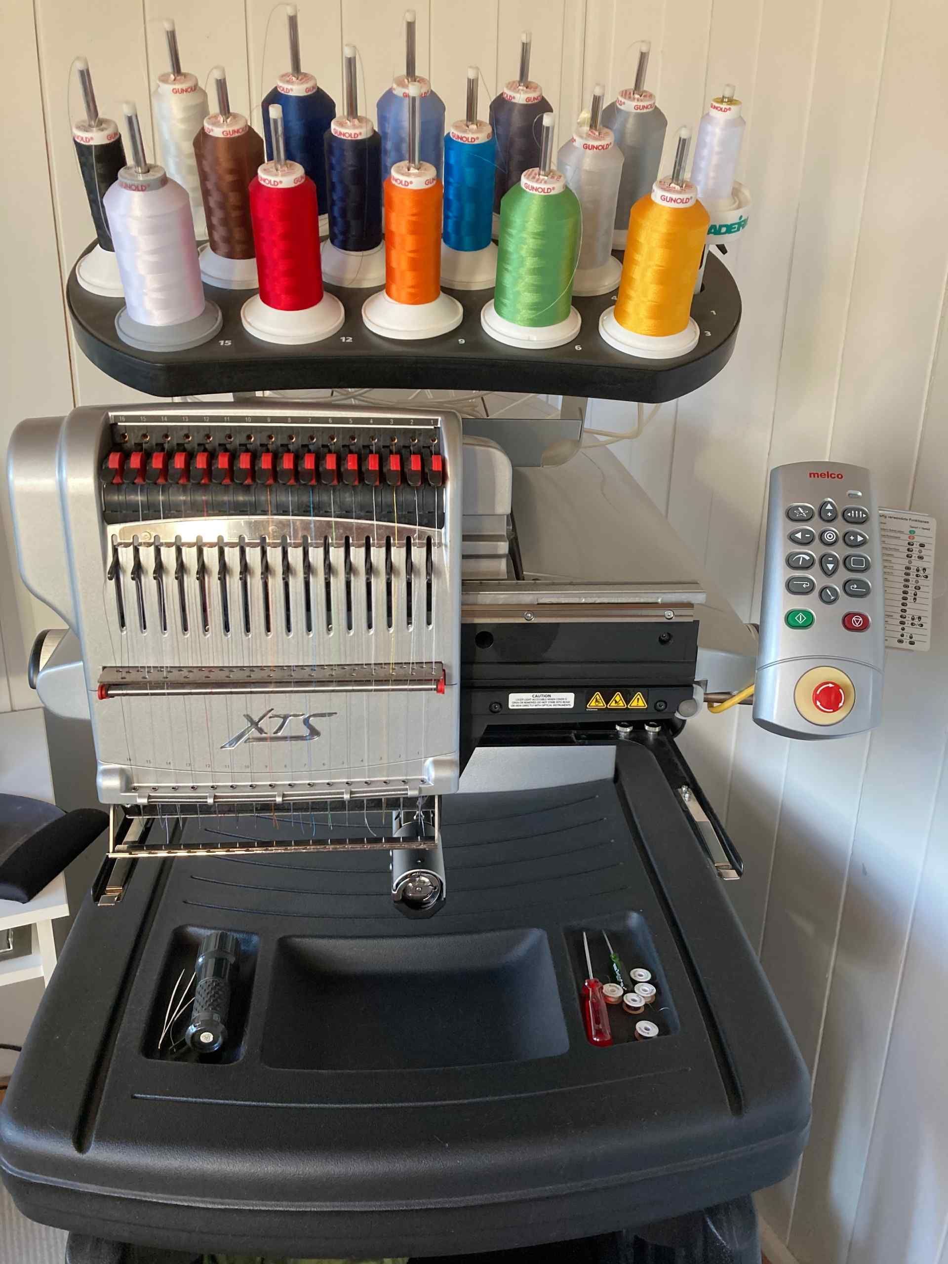 Stickmaschine mit mehreren Garnrollen oben und Bedienfeld.