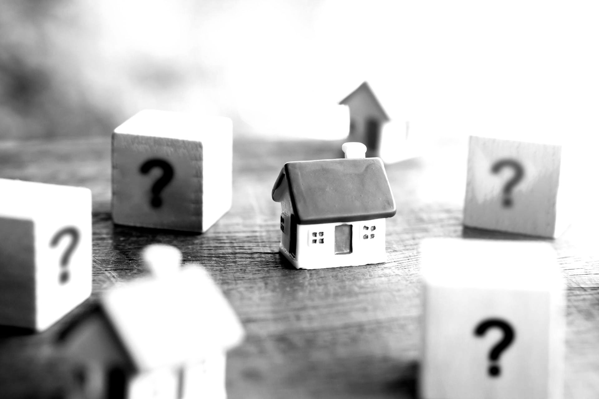 Maison miniature au milieu de carrés avec un point d'interrogation