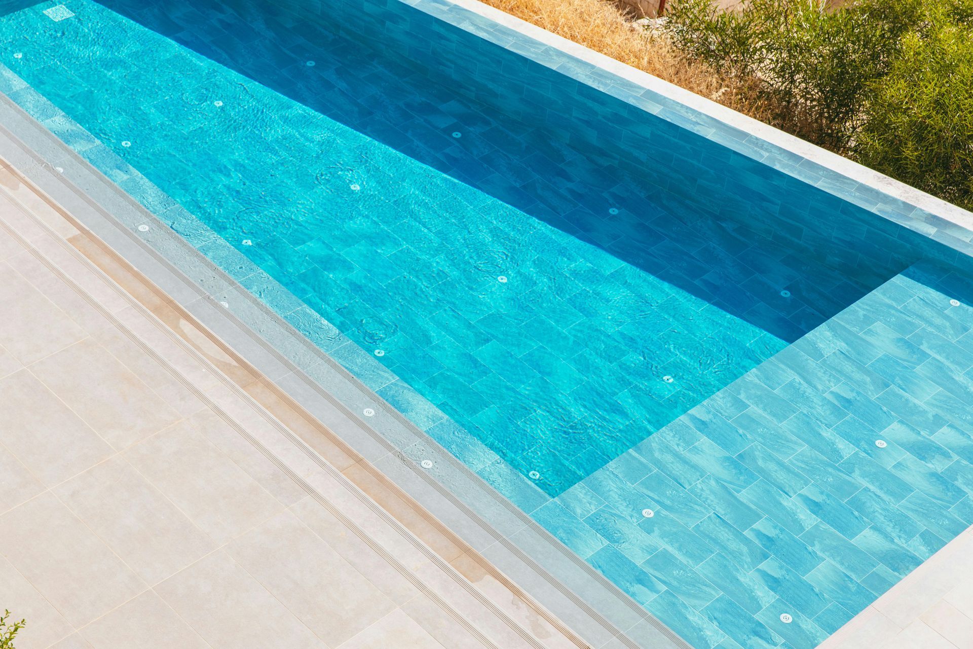 Una piscina rectangular con agua revestida de azulejos de color azul brillante