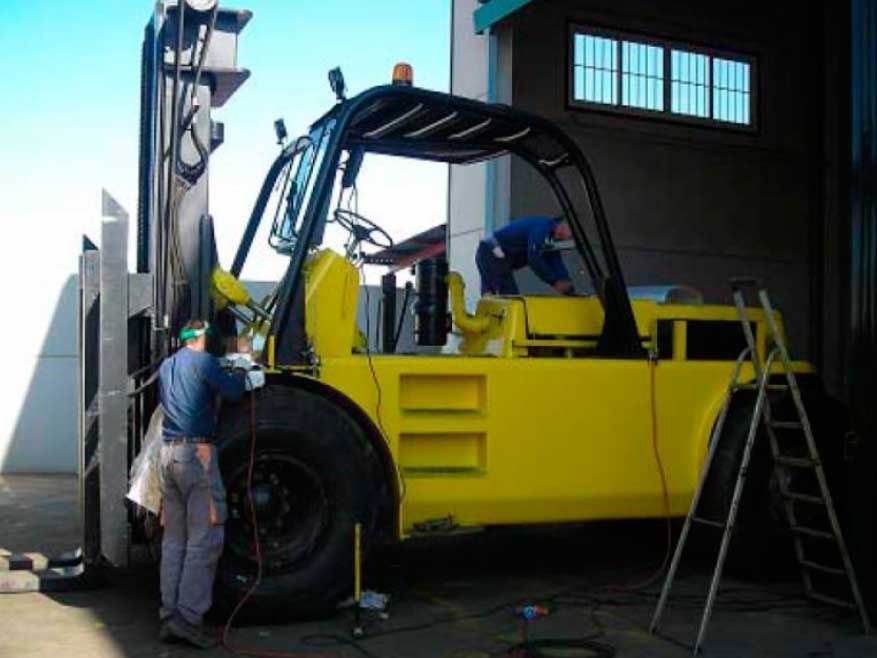 Un hombre está trabajando en una carretilla elevadora amarilla en un garaje.
