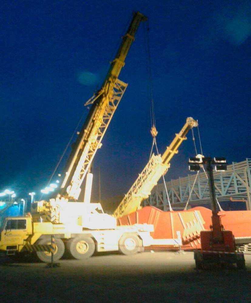 Una gran grúa amarilla está siendo levantada por otra grúa