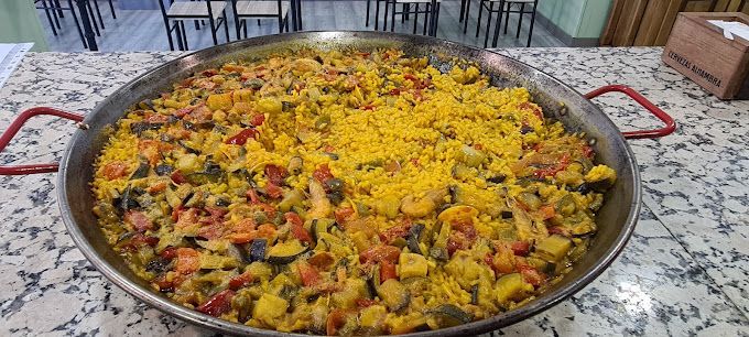 Sobre una encimera hay una cacerola con arroz y verduras.