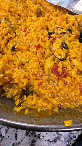 Un primer plano de una sartén de arroz con carne y verduras sobre una mesa.