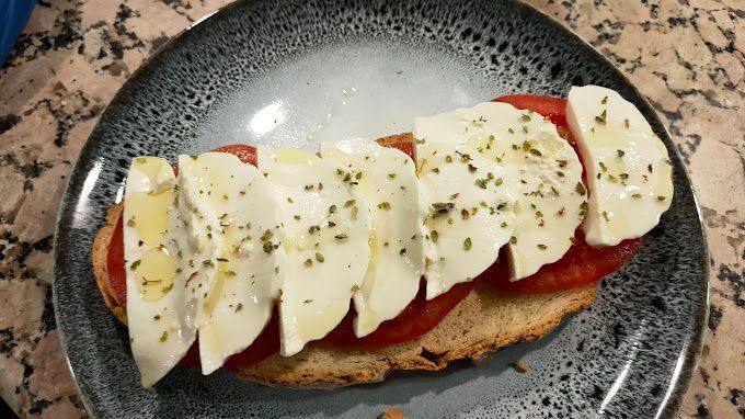 Un primer plano de un plato de comida con mozzarella y tomates en una mesa.