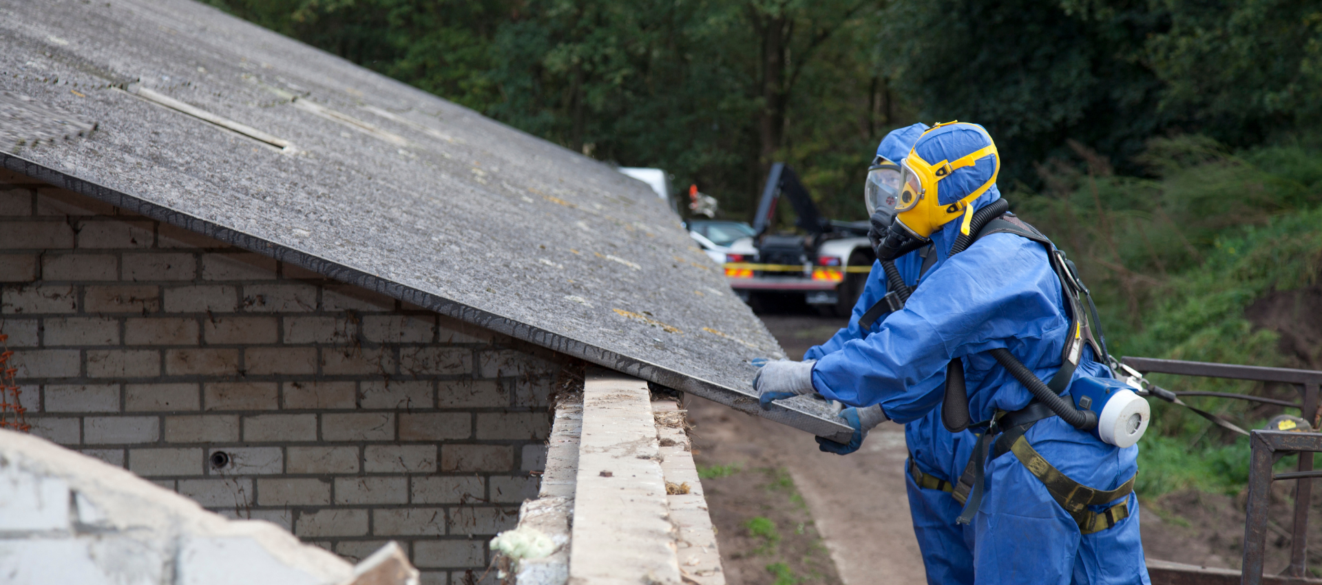 Une personne en combinaison de protection bleue retire des tuiles.