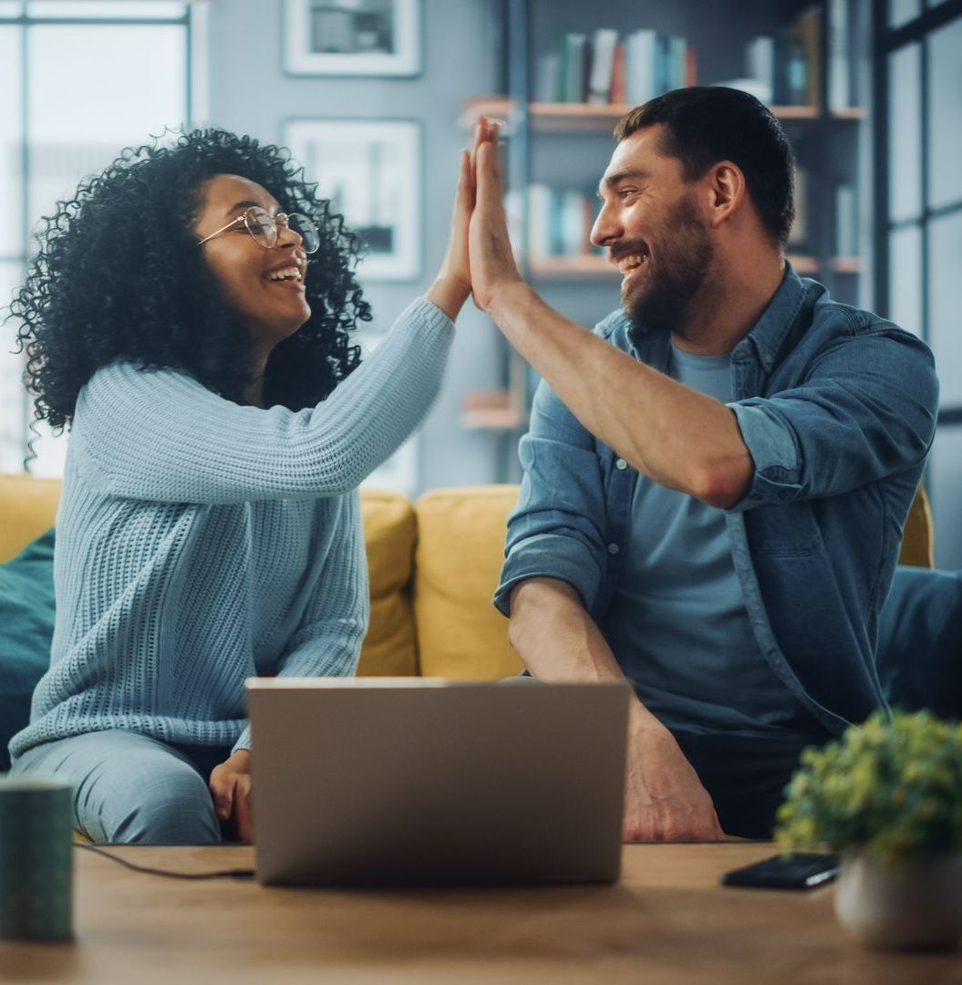 Couple souriant se tapant dans la main devant un ordinateur allumé