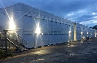 Ein großes weißes Gebäude mit einer Treppe, die nach oben führt, ist nachts beleuchtet.