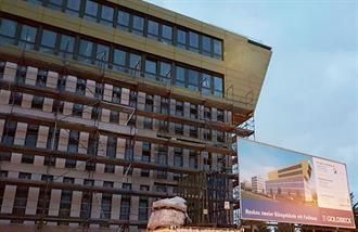 Ein großes im Bau befindliches Gebäude mit einer Plakatwand davor.