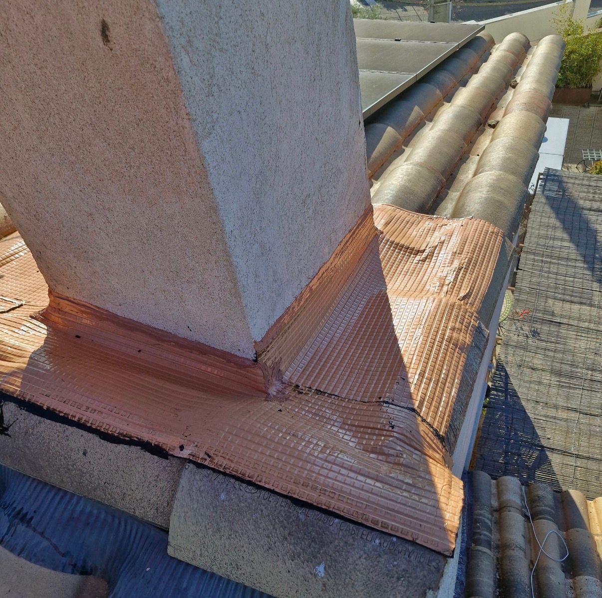 Gros plan sur une cheminée sur un toit de tuiles.