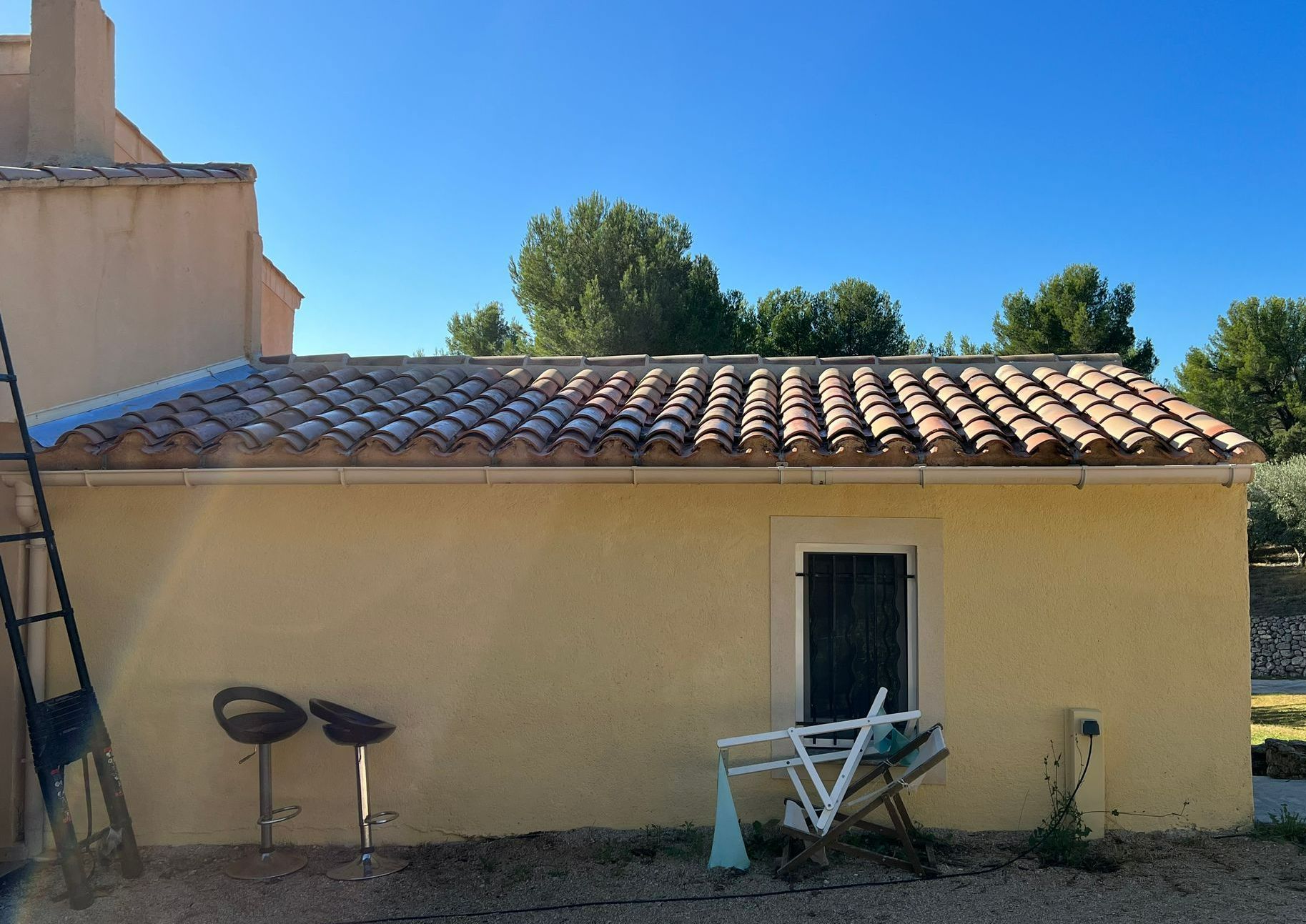 Une toiture en tuile avec un mur jaune.