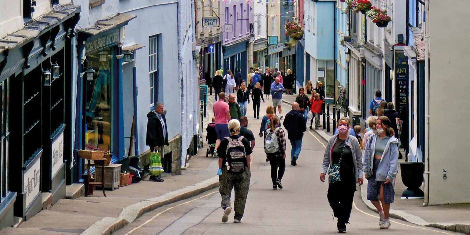 People exploring Falmouth's independent shops and cafés along the town's bustling high street.