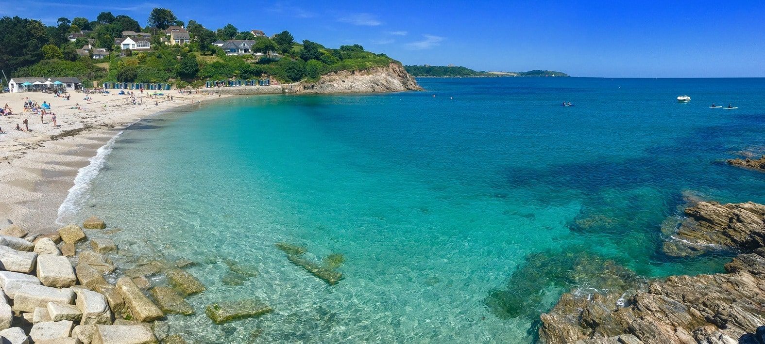 Swanpool Beach near Falmouth with turquoise water, golden sand and people enjoying the beach.
