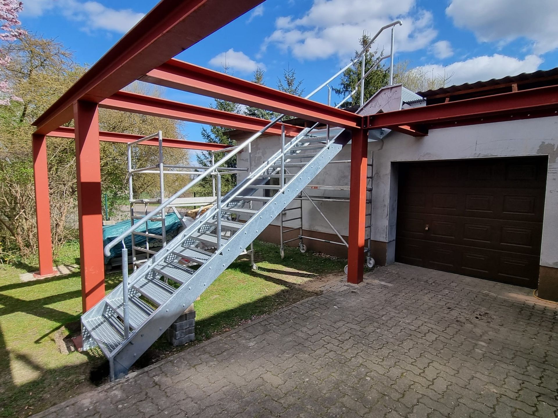 Eine rote Metalltreppenrampe Eine rote Metalltreppenrampe ist an ein Haus neben einer Garage angebaut und führt zu einem erhöhten Eingang.