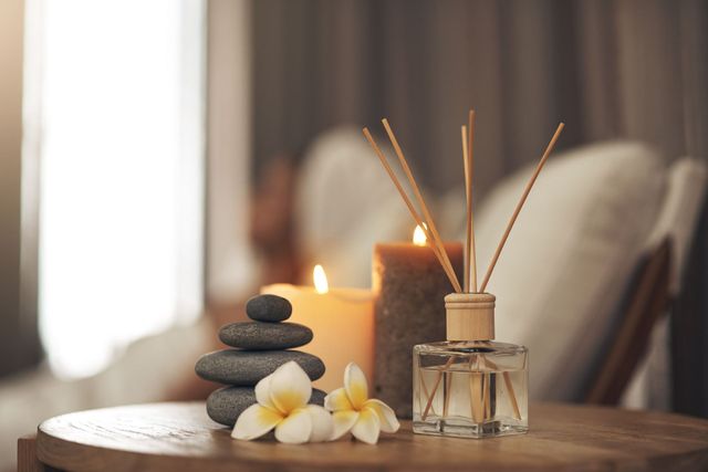 Un amas de pierres, des bougies, un diffuseur et des fleurs sur une table, créant une ambiance digne d'un spa.