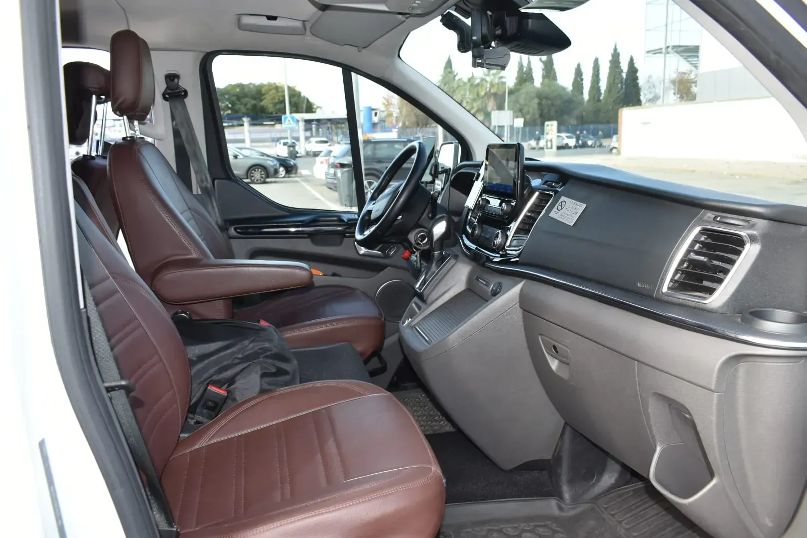 El interior de una furgoneta blanca con asientos de cuero marrón.