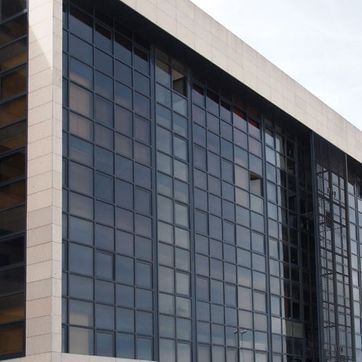 Edificio de oficinas moderno con fachada de cristal y exterior de piedra beige.