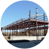 Estructura de acero en construcción sobre cimientos de hormigón bajo un cielo azul.