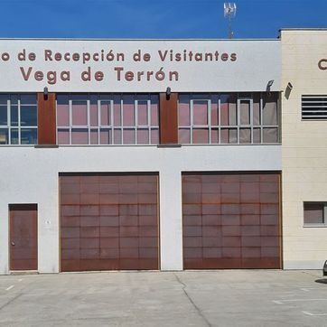 Edificio de recepción para visitantes con la inscripción “Vega de Terrón”, con puertas y ventanas de garaje de color marrón.