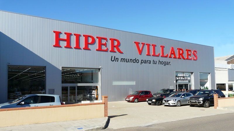 Edificio de concesionario de automóviles con un gran letrero rojo de HIPER VILLARES y coches aparcados en el exterior.