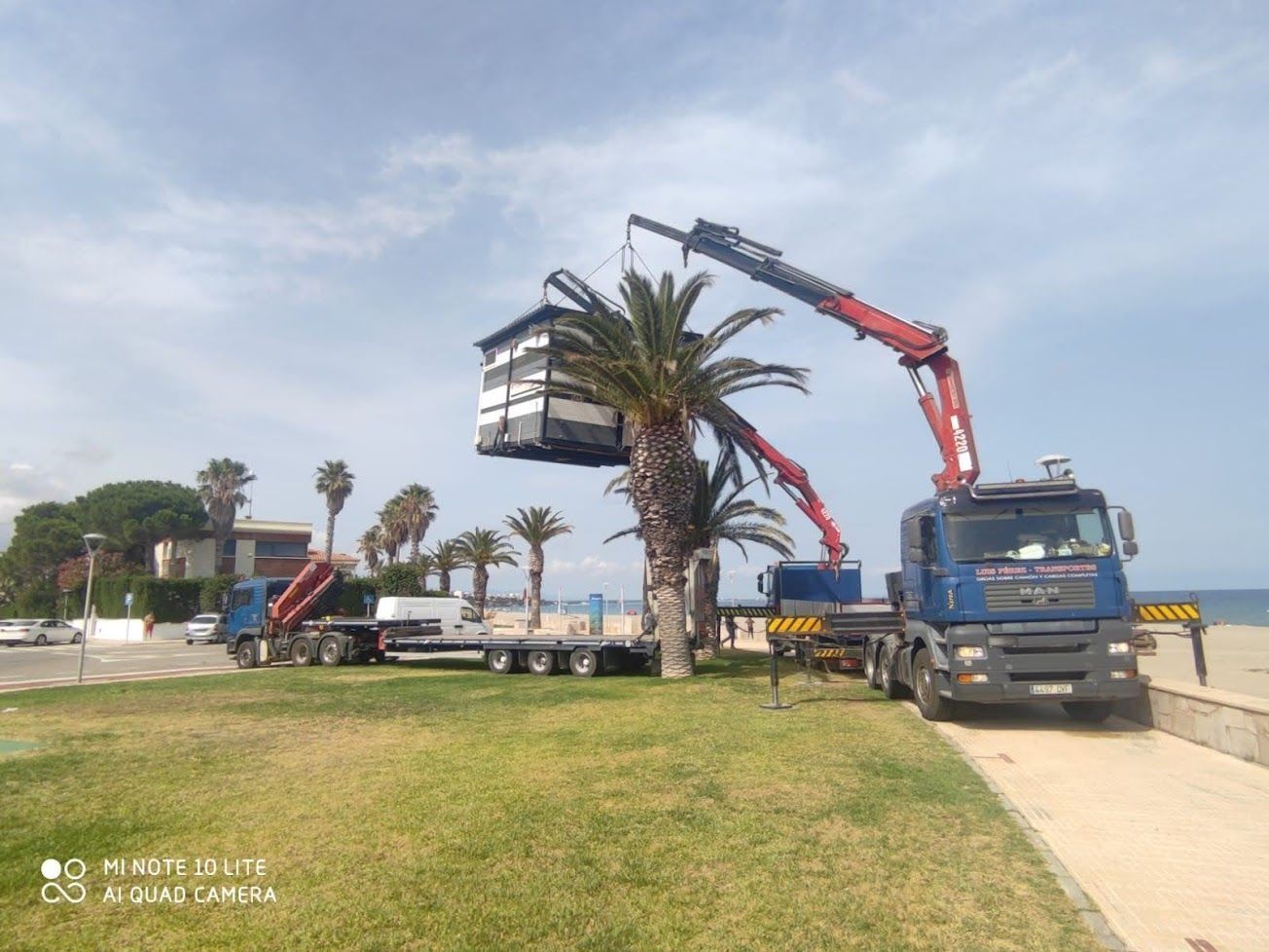Un camión con una grúa acoplada transporta una casa.