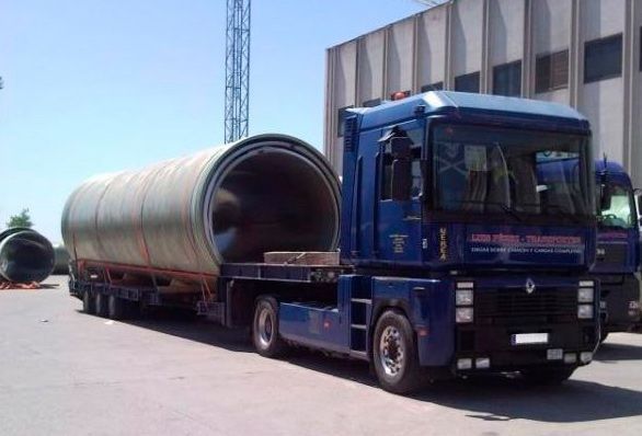 Un camión azul transporta un objeto cilíndrico grande.