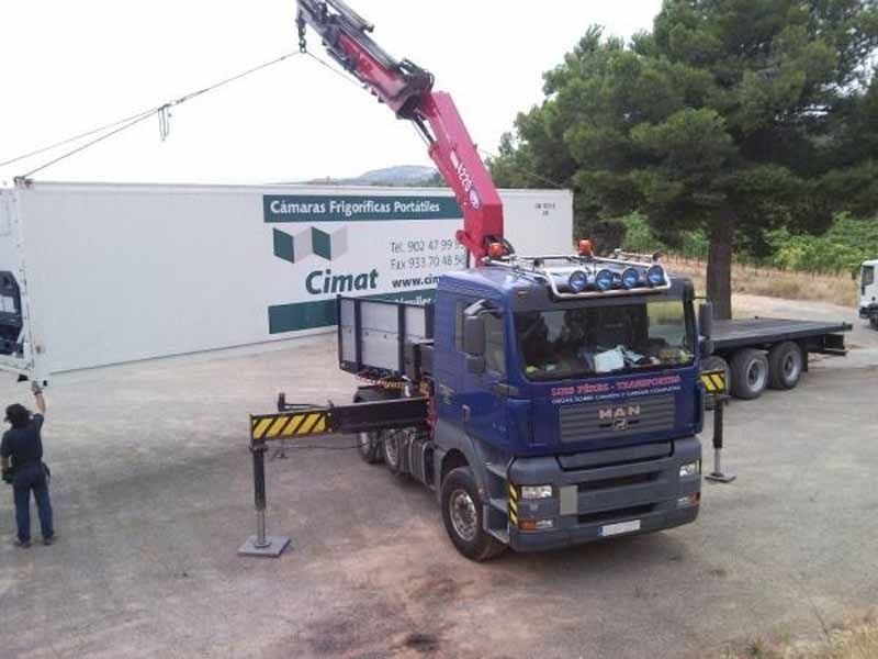 Un hombre está parado al lado de un camión con una grúa adjunta.