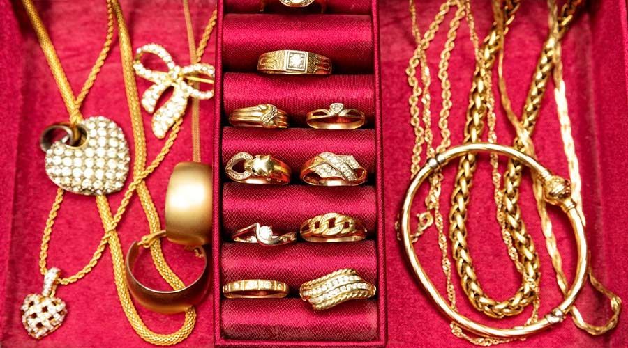 Conjunto de joyas de oro expuesto sobre terciopelo rojo, que incluye collares, anillos, brazaletes y un colgante en forma de corazón.