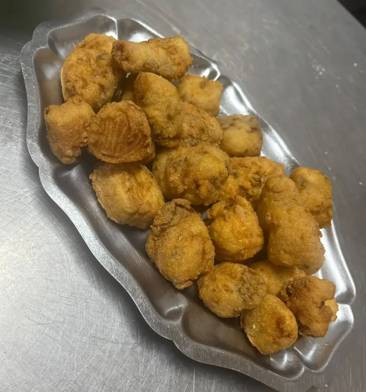 Bandeja de aperitivos fritos dorados sobre una fuente de plata.
