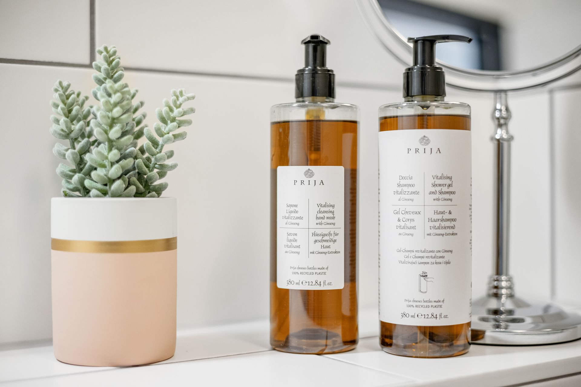 Zwei Seifenflaschen stehen auf einer Badezimmerablage neben einer Topfpflanze.