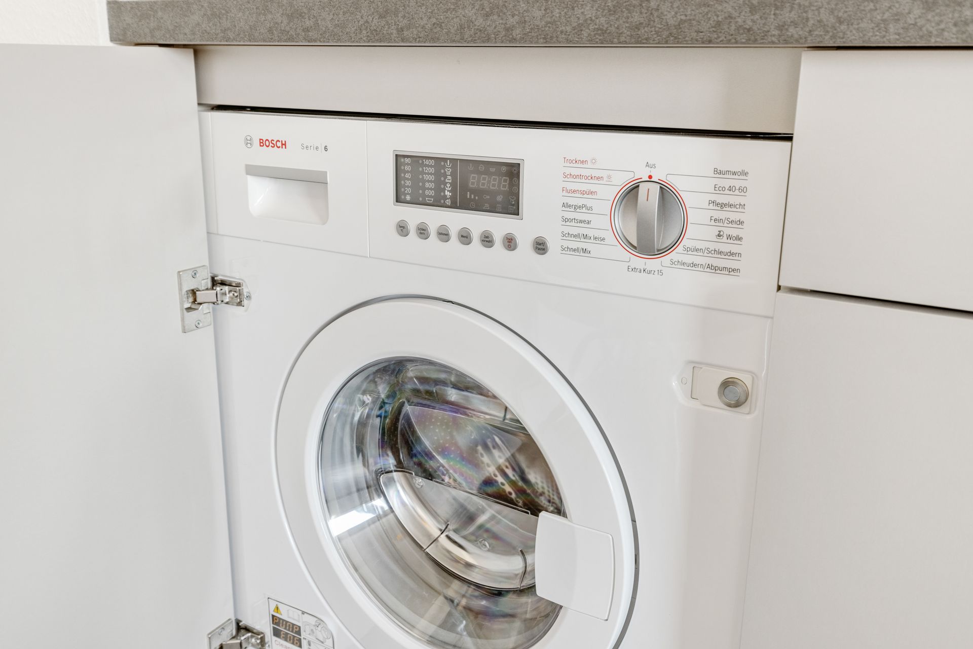 Eine weiße Waschmaschine ist in einen Küchenschrank von einer Ferienwohnung in Denzlingen eingebaut.