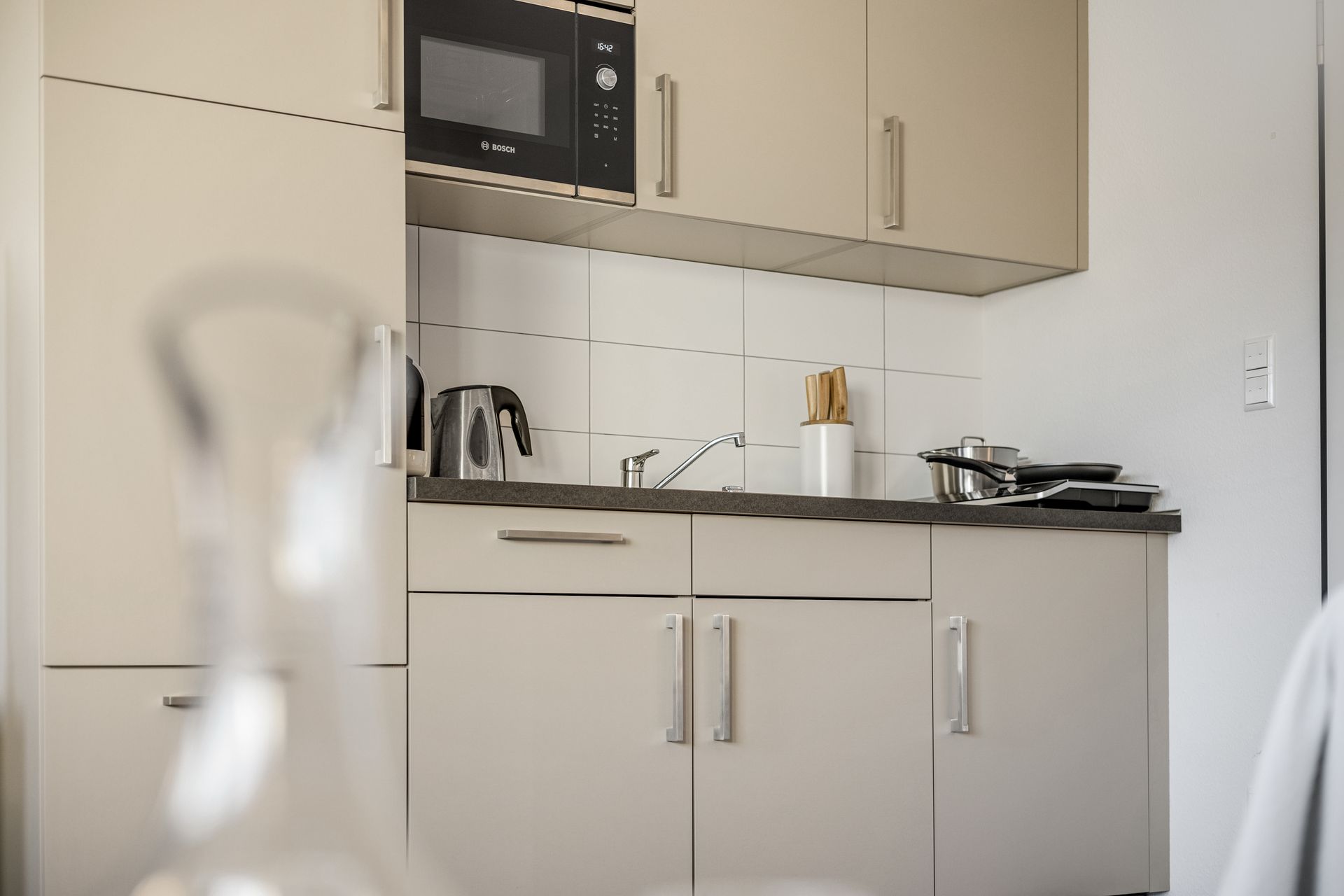 Eine Küche mit Kaschmir Schränken und einer Mikrowelle in einer Ferienwohnung nahe Waldkirch.