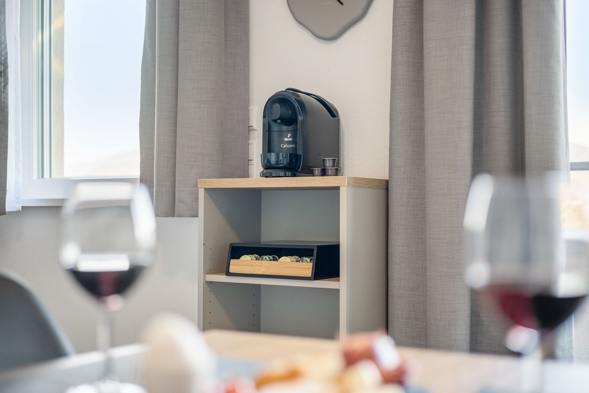 Auf einem Regal in Denzlingen neben einem Tisch steht eine Kaffeemaschine, auf der zwei Gläser Wein stehen.