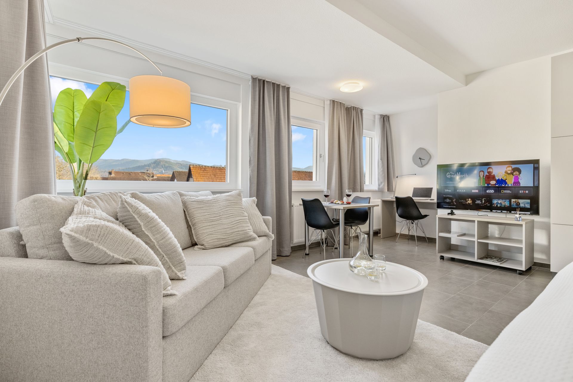 Ein Apartment mit Couch, Tisch und Fernseher.