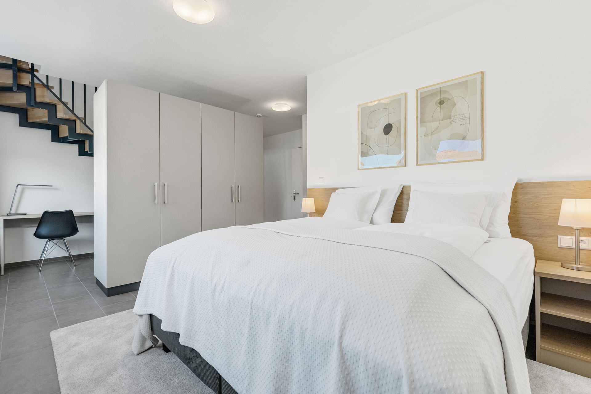 Ein Schlafzimmer mit großem Bett, Treppe und Schreibtisch.