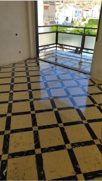 Una habitación con suelo de cuadros y balcón.