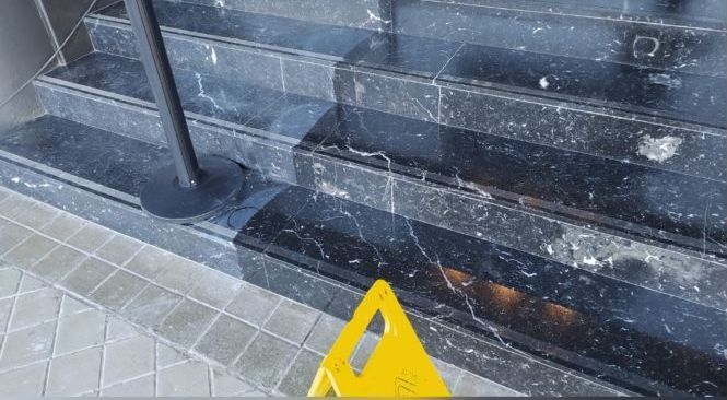 Un cartel amarillo de piso mojado está al lado de un tramo de escaleras.