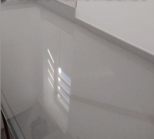 Un primer plano de una encimera blanca con el reflejo de una ventana.