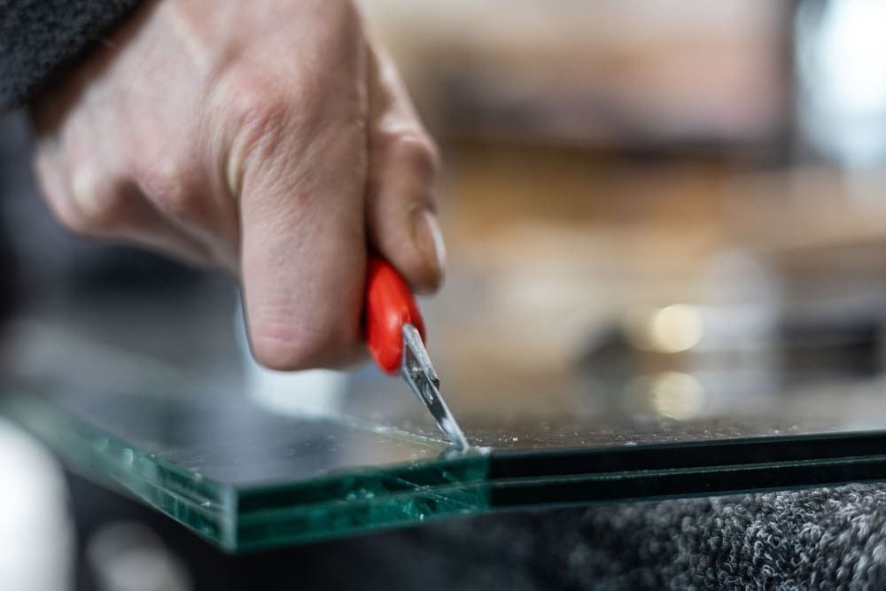Eine Person schneidet ein Stück Glas mit einer Schere.