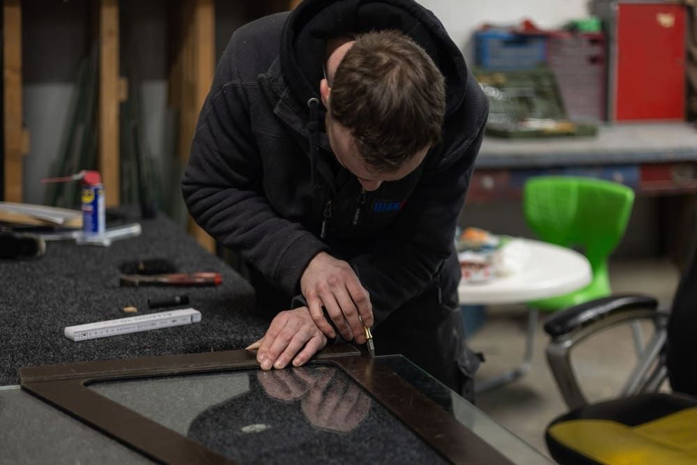 Ein Mann bearbeitet in einer Werkstatt ein Stück Glas.