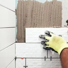 Una persona está instalando azulejos en la pared de un baño.