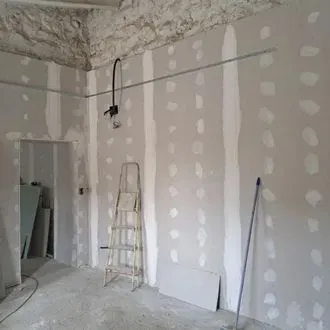 Se está remodelando una habitación con una escalera y un trapeador dentro.