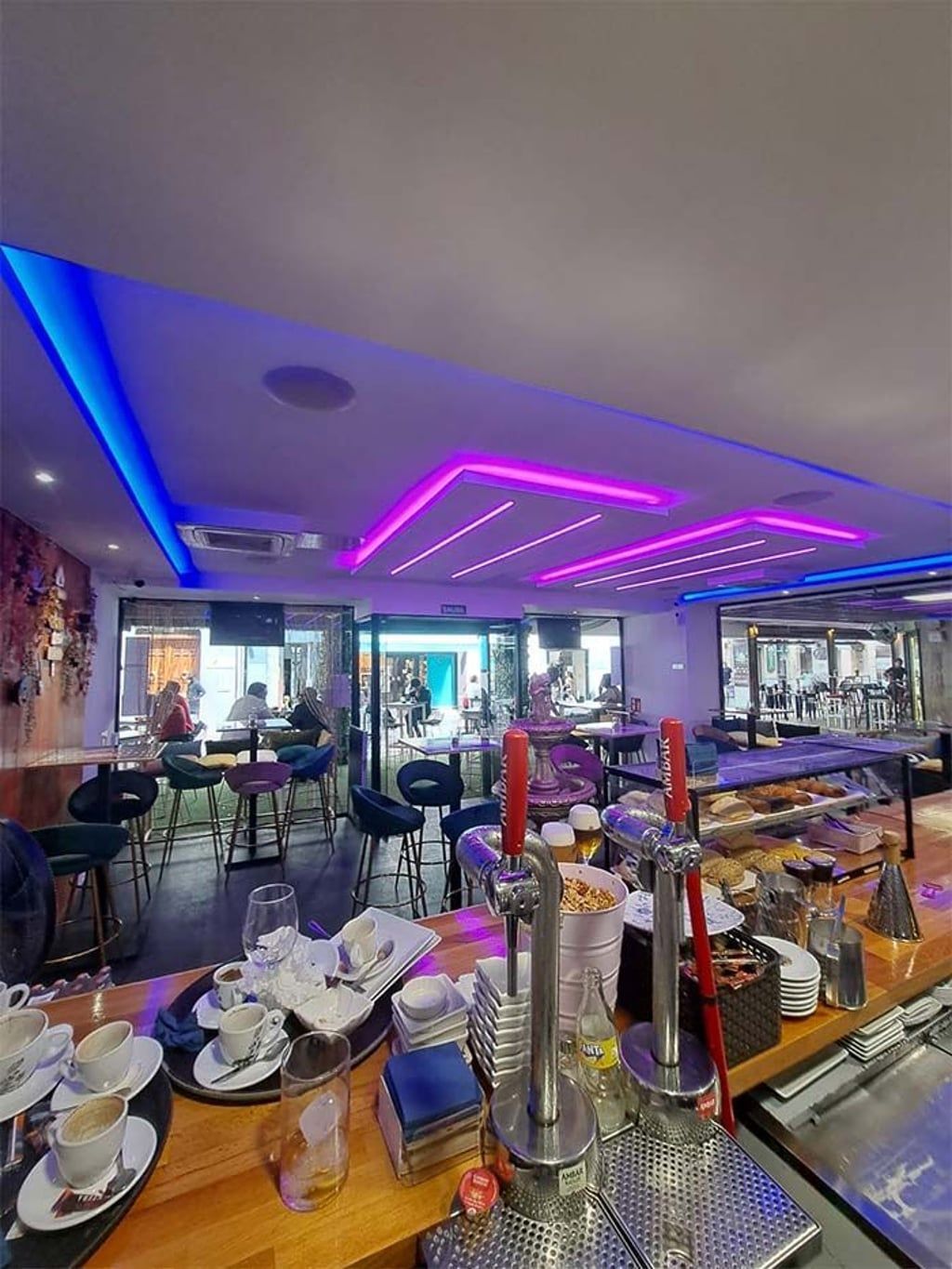 Un restaurante con mesas, sillas, una barra y un techo morado.