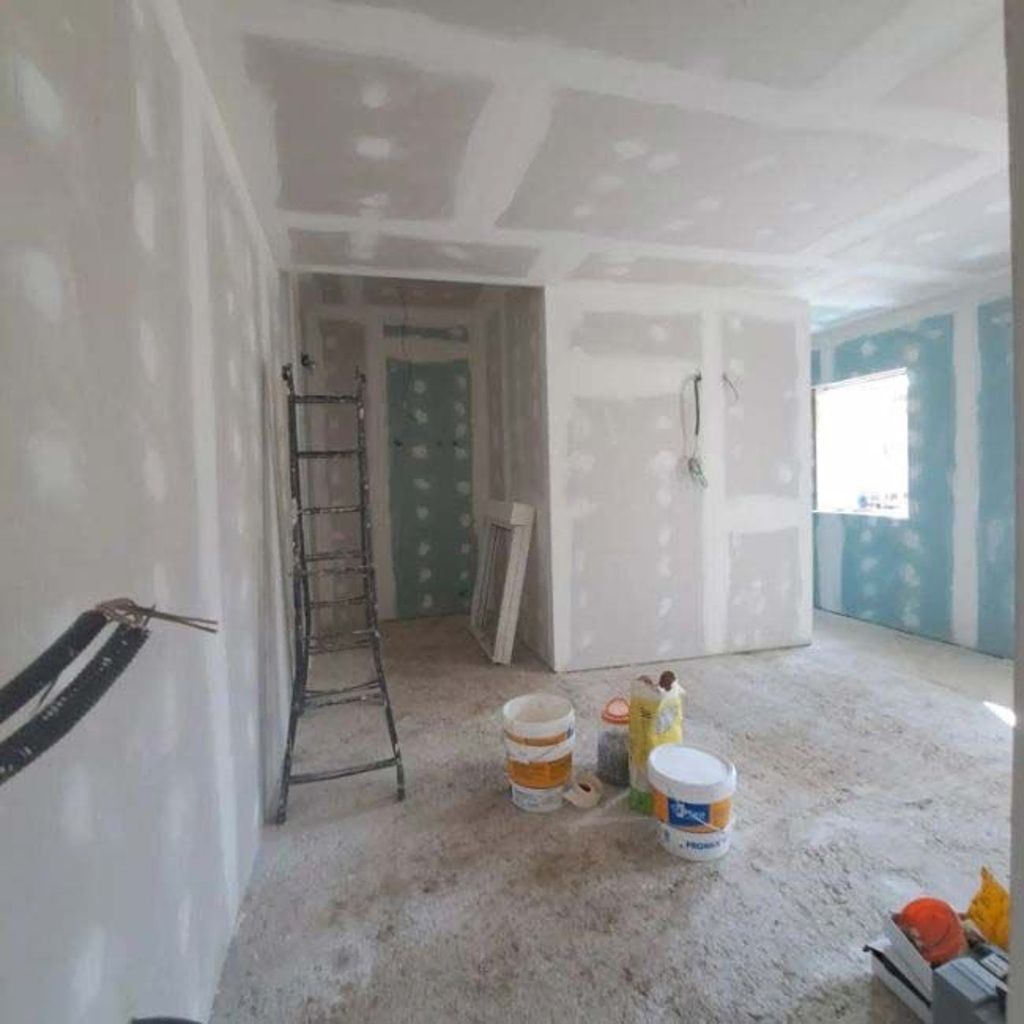 Una habitación con cubos de pintura y una escalera dentro.