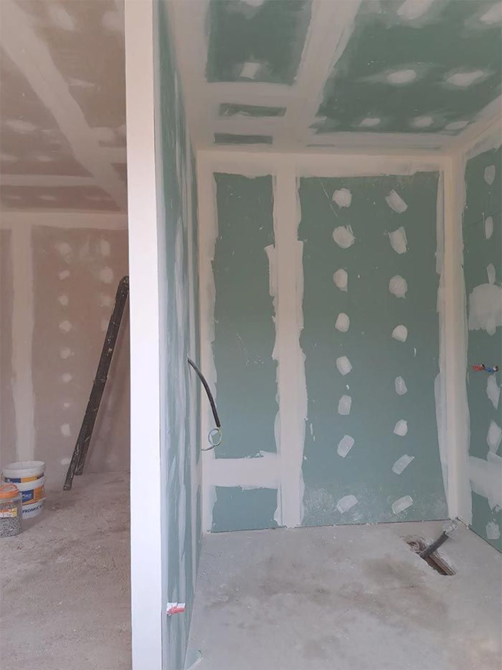 Se está remodelando una habitación con una escalera y un balde de pintura dentro.