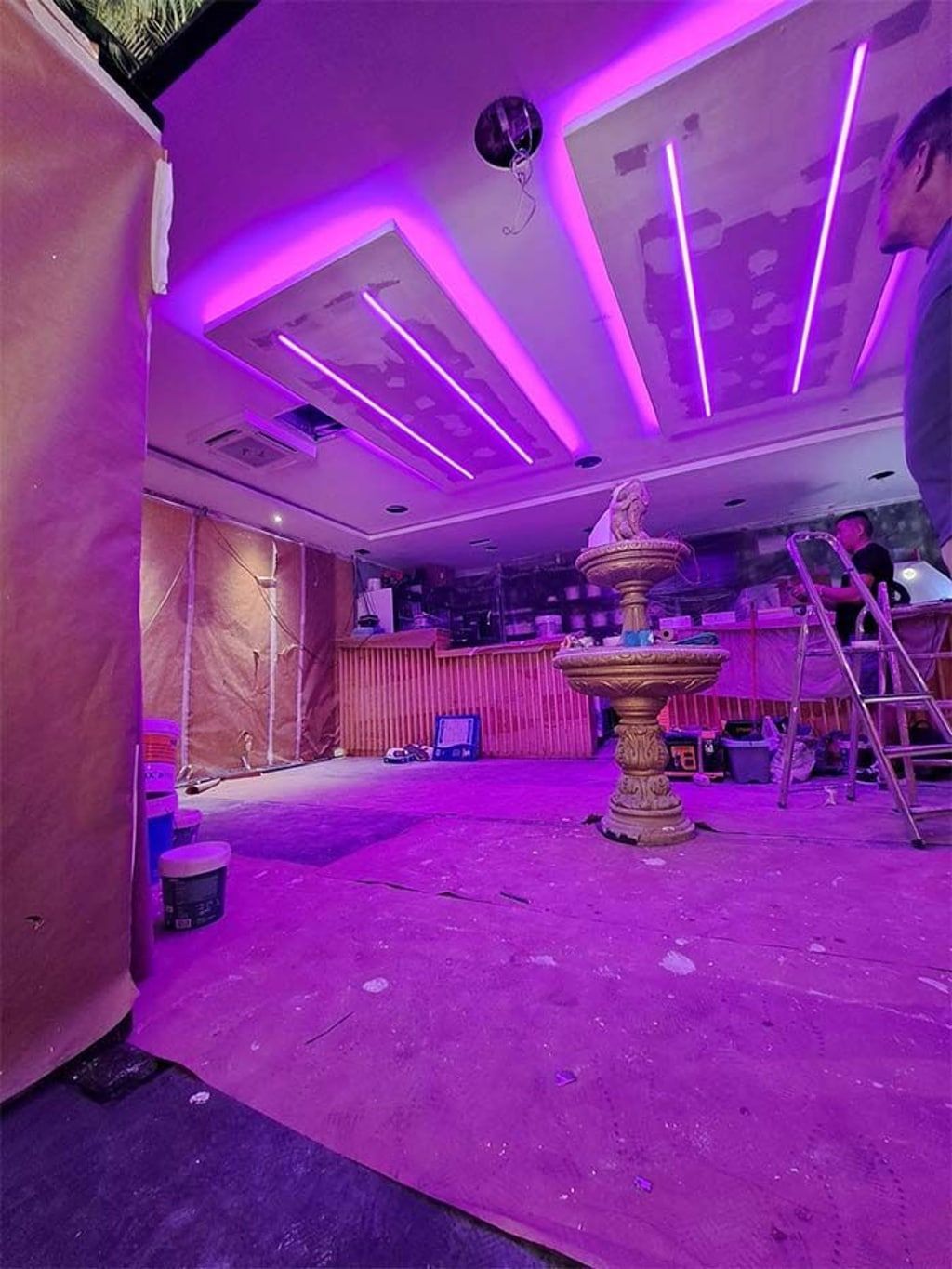 Una habitación con luces violetas en el techo y una fuente en el medio.