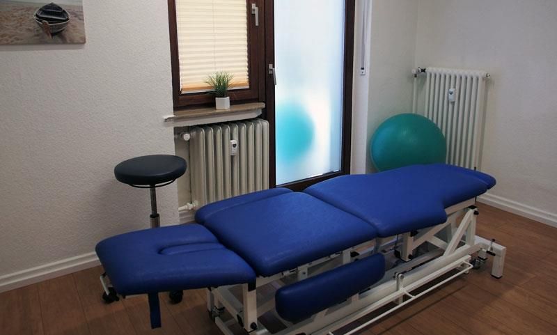 Eine blaue Massageliege in einem Raum neben einem Fenster