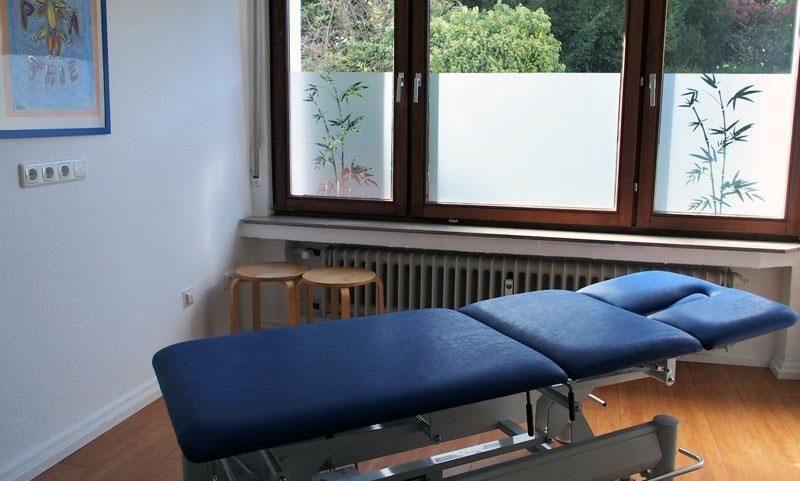 Eine blaue Massageliege in einem Raum mit Fenster