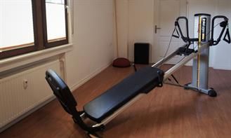 In einem Raum neben einem Fenster steht eine Pilates-Maschine.