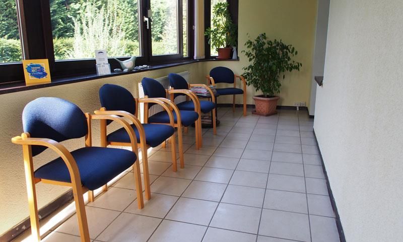 Ein Wartezimmer mit blauen Stühlen und einer Pflanze
