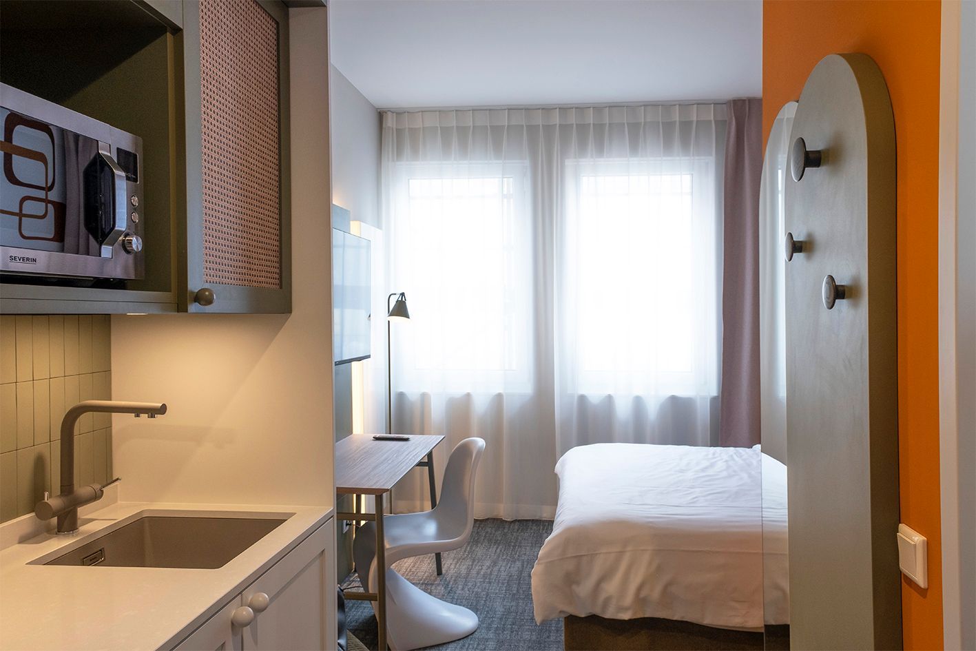 Ein Hotelzimmer mit Bett, Schreibtisch, Waschbecken und Mikrowelle